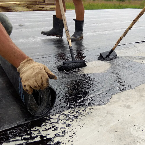 Roofer painting bitumen primer